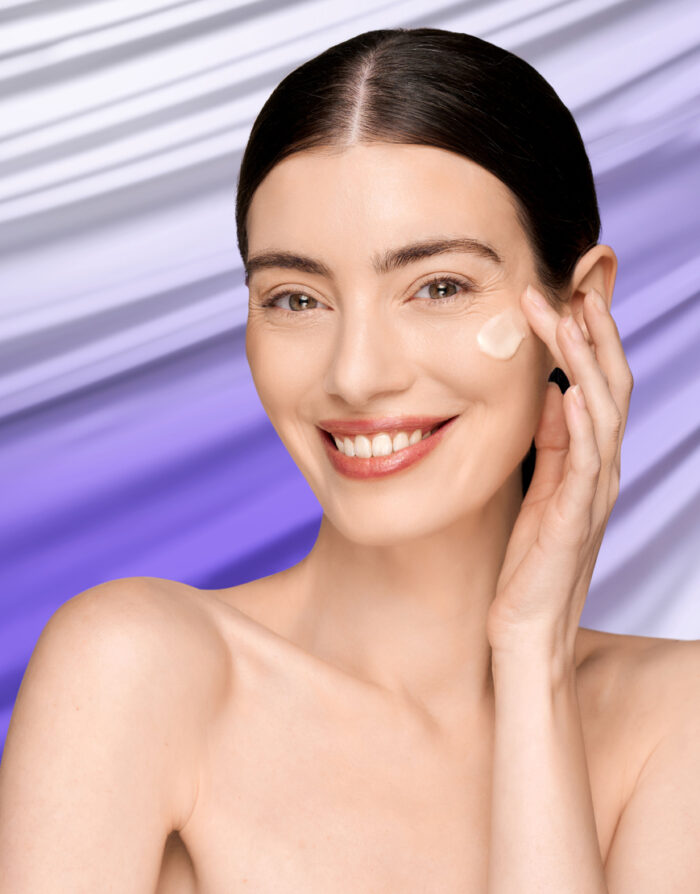 Modella sorridente che applica Liftable Exoserum sullo zigomo